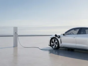 Witte elektrische auto aan minimalistische laadpaal op betonnen platform onder open hemel