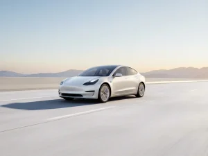 Witte elektrische sedan op lege betonnen snelweg richting bergen, gouden uur verlichting benadrukt aerodynamisch design