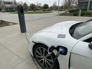 Witte elektrische auto laadt op bij moderne laadpaal met minimalistische laadpas op motorkap in zakelijke parkeergarage