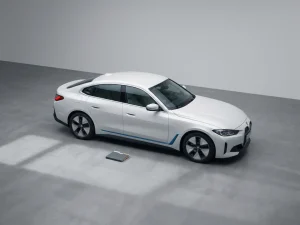 Witte elektrische auto op betonnen ondergrond met documentenmap naast voorwiel, minimalistische compositie